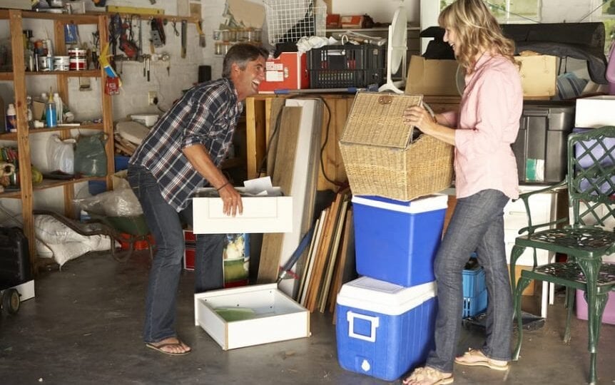 couple moving items in messy garage